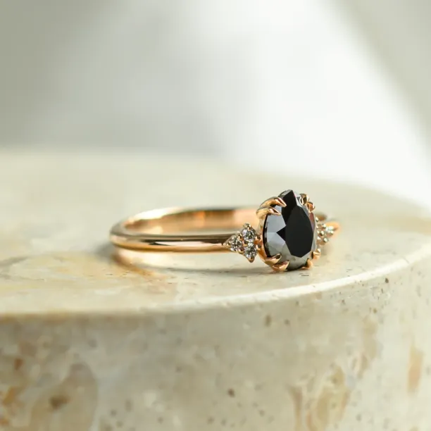 Angled view of the BLACKIE engagement ring with a black pear diamond and side diamonds