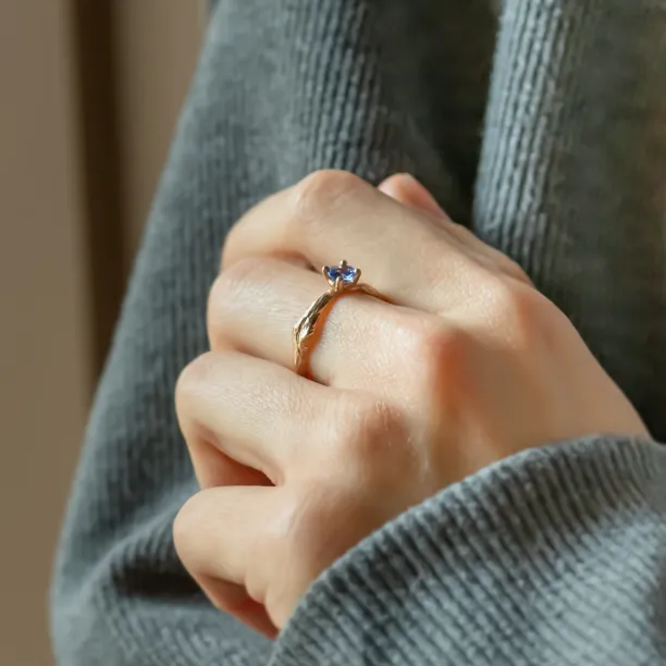 Angled view of the DREMIS tanzanite gold ring worn on a hand