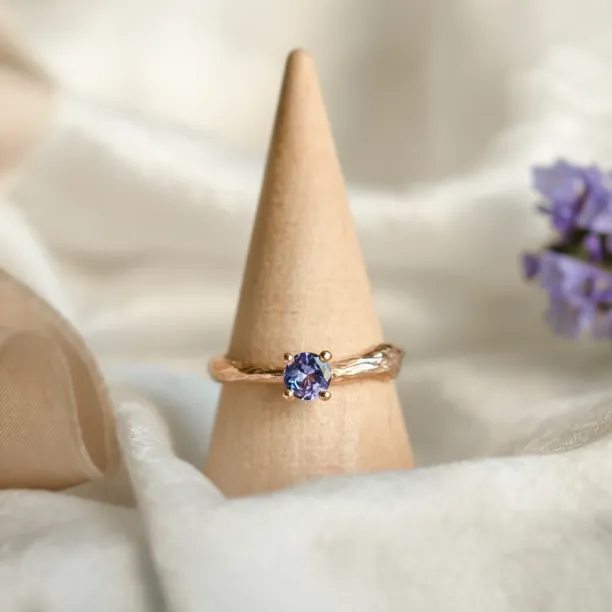 DREMIS gold tree branch ring with tanzanite displayed on a ring stand