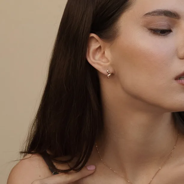 MIGNON gold wave earring worn on the ear, close-up