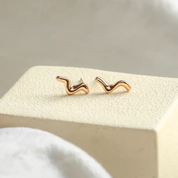 Angled view of MIGNON minimalist gold wave earrings