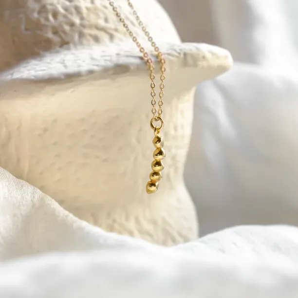 Angled view of the gold CORINNE necklace and beaded pendant