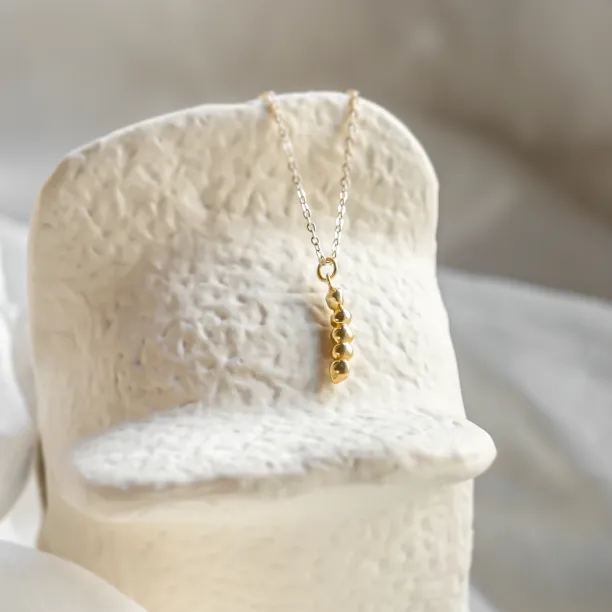 Angled view of the gold CORINNE necklace with its diamond pendant