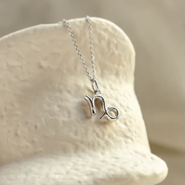 Angled close-up of the gold diamond CAPRICORN pendant