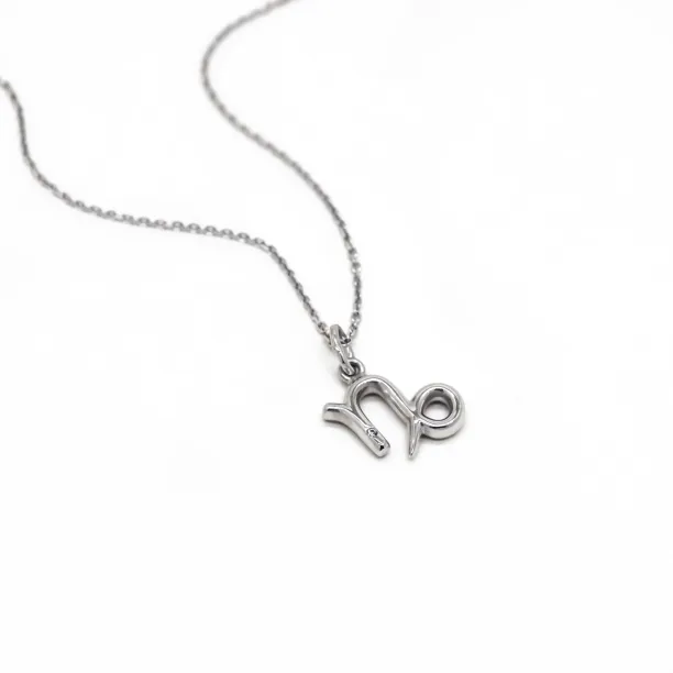 Gold diamond CAPRICORN pendant lying flat with chain