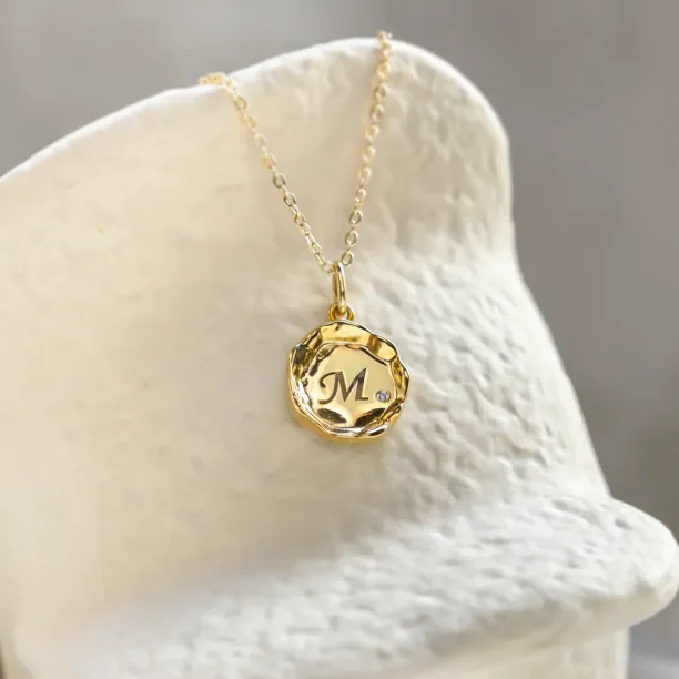COLETTE gold pendant with engraved M and diamond in a close-up view