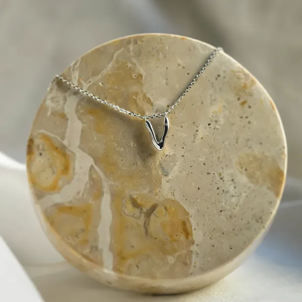 Gold letter V pendant with diamond on a chain, angled view