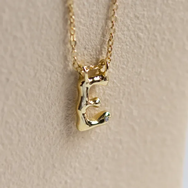 Close-up of the side of a gold letter A pendant with diamond