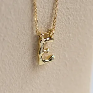 Close-up of the side of a gold letter A pendant with diamond