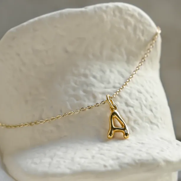 Close-up of a gold letter A pendant with diamond on a chain