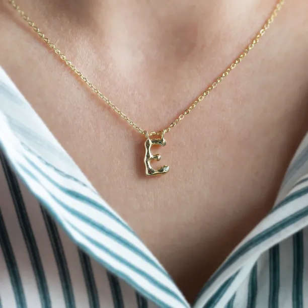 Gold letter E pendant with diamond worn on the neck