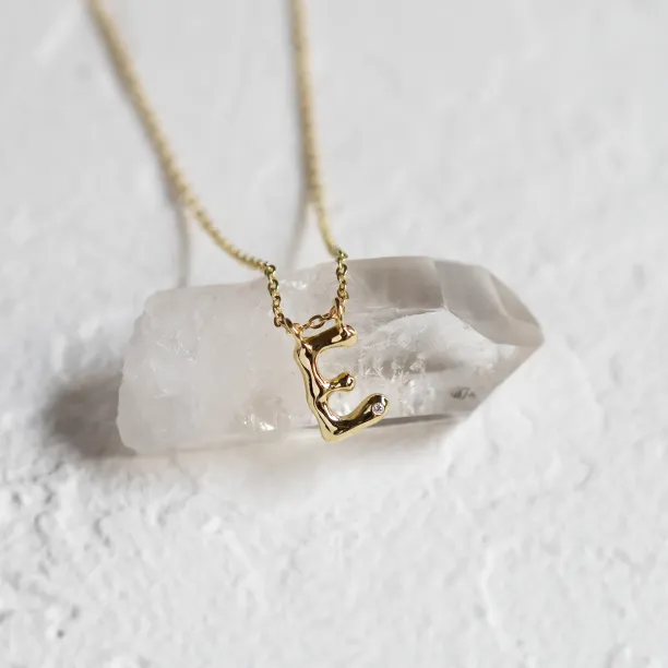 Close-up of a gold letter E pendant with a diamond on a chain