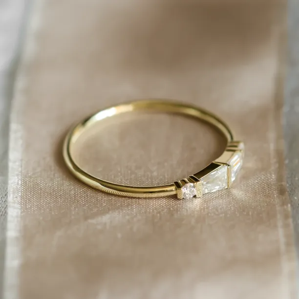 Angled view of LUMI gold ring with baguette and round moissanites