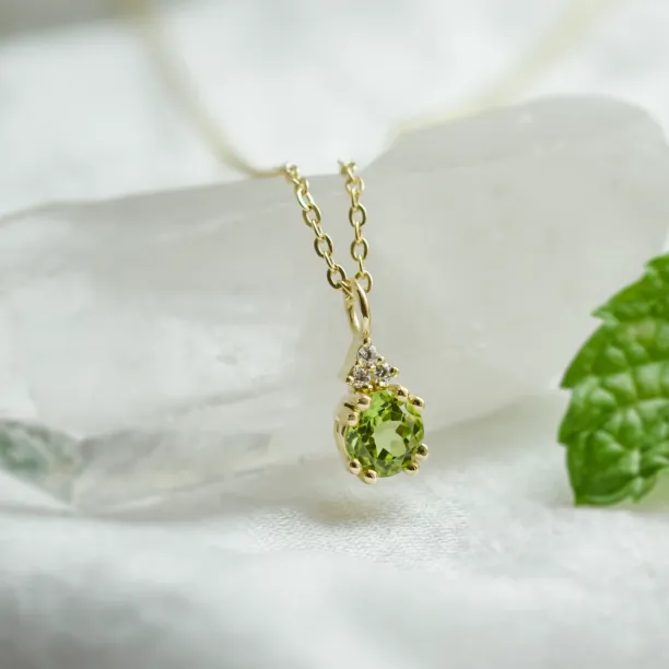 Angled view of the gold peridot and diamond pendant