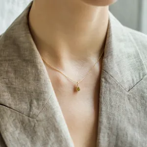 Gold peridot and diamond pendant worn on the neck, close-up