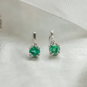 Close-up of paired LENNY gold earrings with emeralds and diamonds