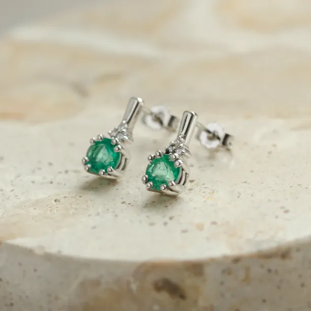 Angled close-up of LENNY gold earrings with emeralds and diamonds