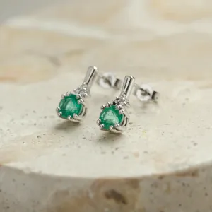 Angled close-up of LENNY gold earrings with emeralds and diamonds