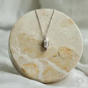 Zlatý přívěsek FINA s hexagon moissanitem položený na kamenném podkladu
