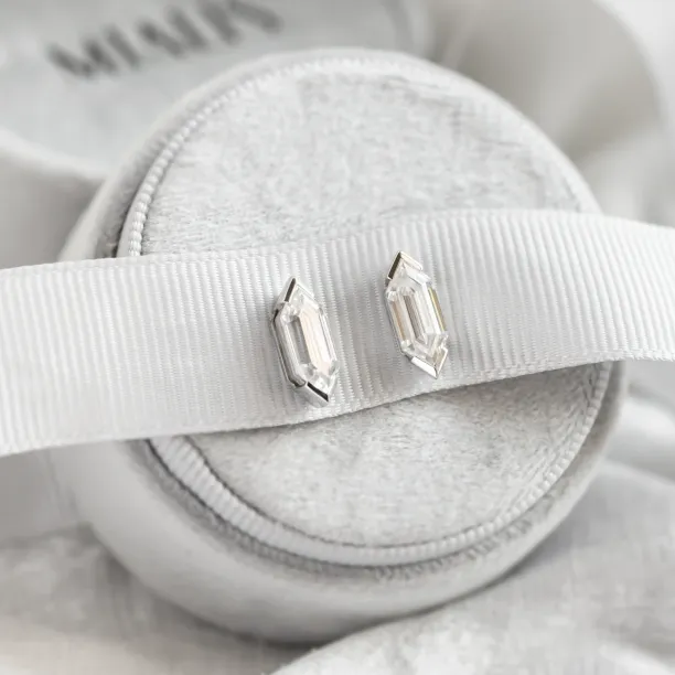 Pair of SERENA geometric moissanite earrings on a display cushion