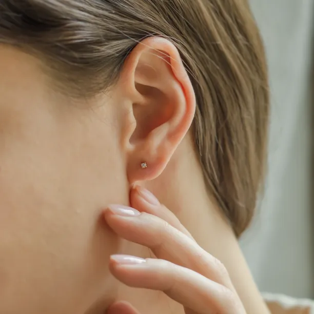 Náušnice ALINE s lab-grown diamantem v uchu, dotýká se jí ruka
