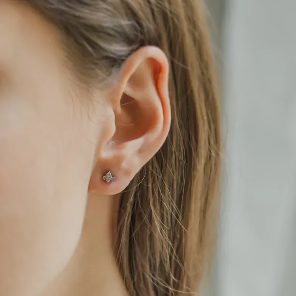 Gold diamond cluster earring worn on the ear, angled view
