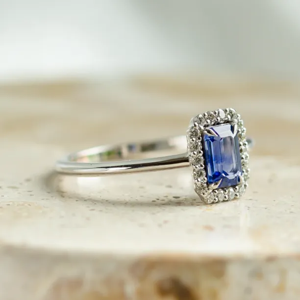 Close-up of the LEAR engagement ring with a baguette teal sapphire and diamond halo