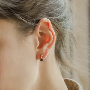 Close-up of a SEAN gold stud earring with black diamond, worn on the ear