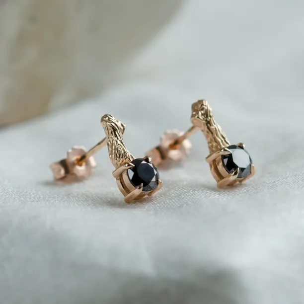 Angled view of SEAN gold stud earrings with black diamonds and twig details
