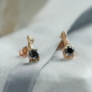 Close-up angled view of SEAN stud earrings with black diamonds and twig details