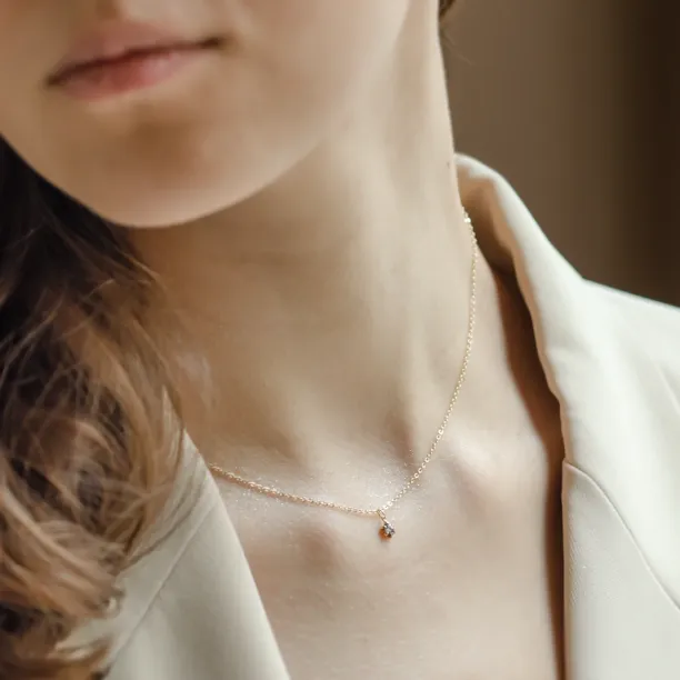 Close-up of the CADIE gold pendant with salt and pepper diamond worn on the neck