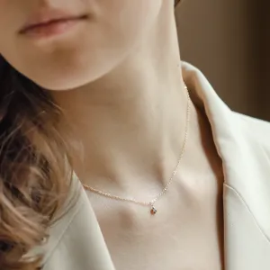 Close-up of the CADIE gold pendant with salt and pepper diamond worn on the neck