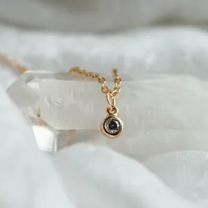 Close-up of the gold pendant with a bezel-set salt and pepper diamond