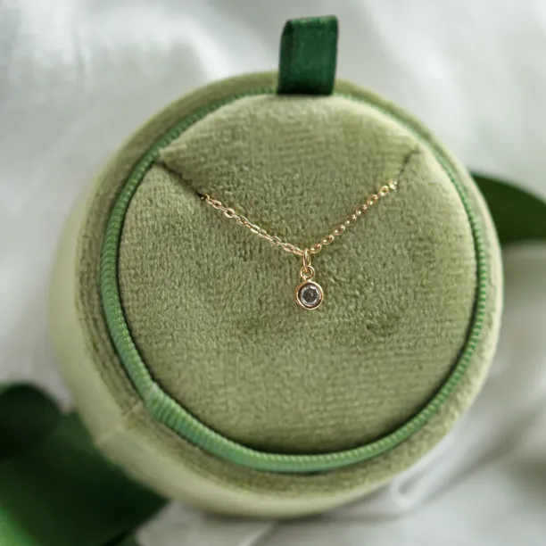 Full view of the gold SAND necklace with its bezel-set diamond pendant