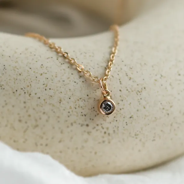 Close-up of the gold chain and bezel-set salt and pepper diamond pendant