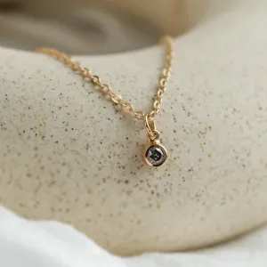Close-up of the gold chain and bezel-set salt and pepper diamond pendant