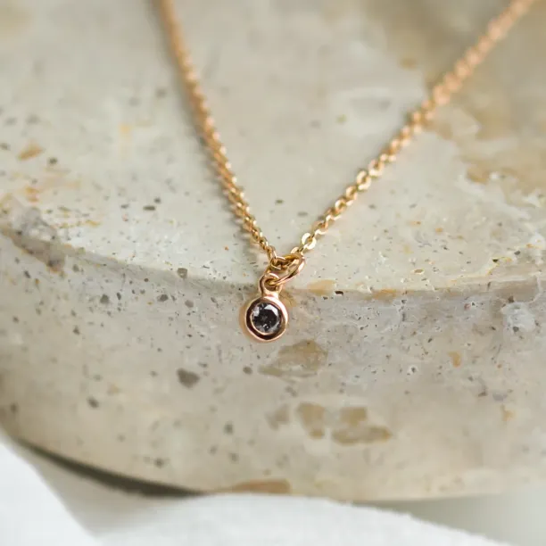 Close-up of the gold SAND pendant and its salt and pepper diamond