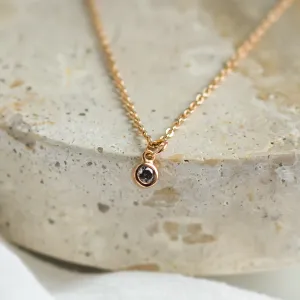 Close-up of the gold SAND pendant and its salt and pepper diamond