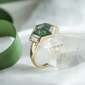 Detailní šikmý pohled na zlatý prsten CALEN s hexagonálním mechovým achátem a baguette moissanity