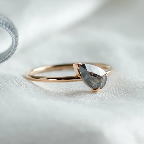 Angled close-up of the ALIA pear-shaped salt and pepper engagement ring