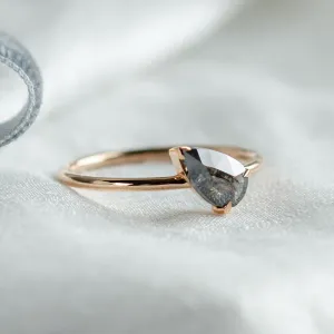Angled close-up of the ALIA pear-shaped salt and pepper engagement ring