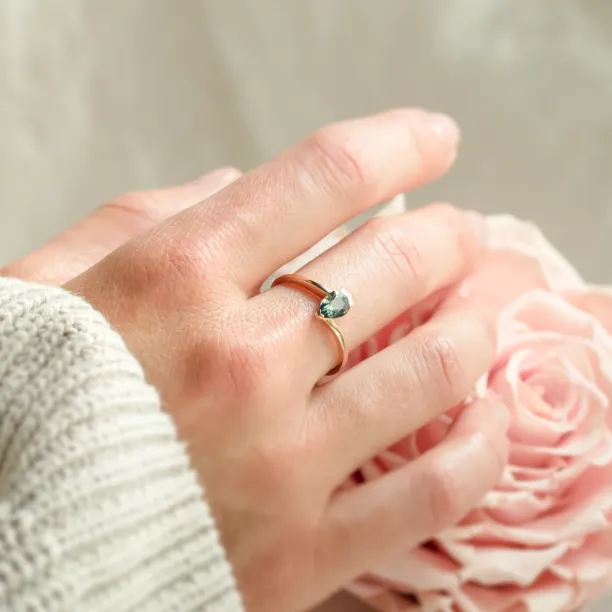 LEAH gold ring with a teal sapphire and diamonds worn on the hand