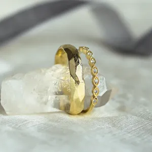 Angled close-up of DARLING diamond wedding bands and hammered surface