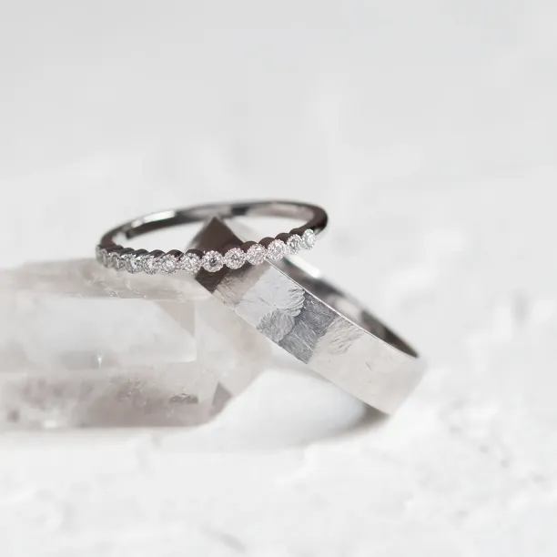 Close-up of the diamond eternity ring resting over the hammered wedding band