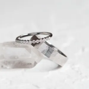 Close-up of the diamond eternity ring resting over the hammered wedding band