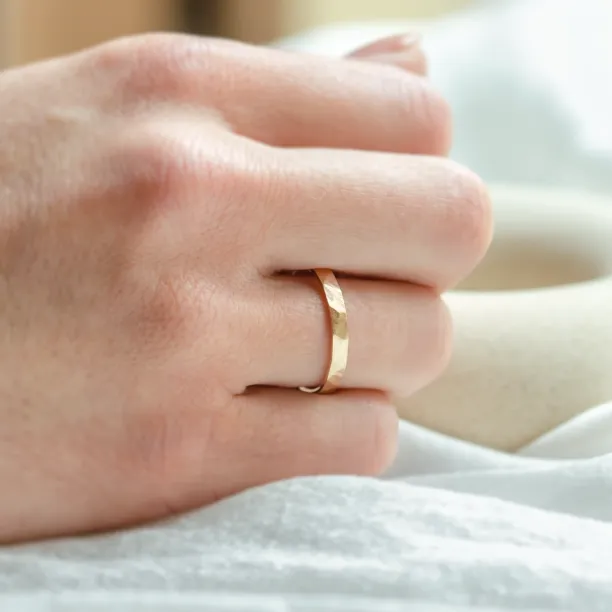 PAIR wedding ring worn on a hand, showing its hammered surface