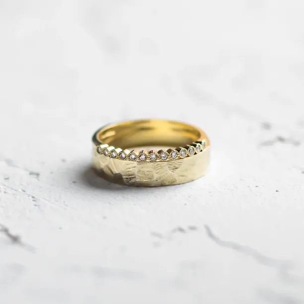 Close-up of a diamond wedding ring with a hammered surface