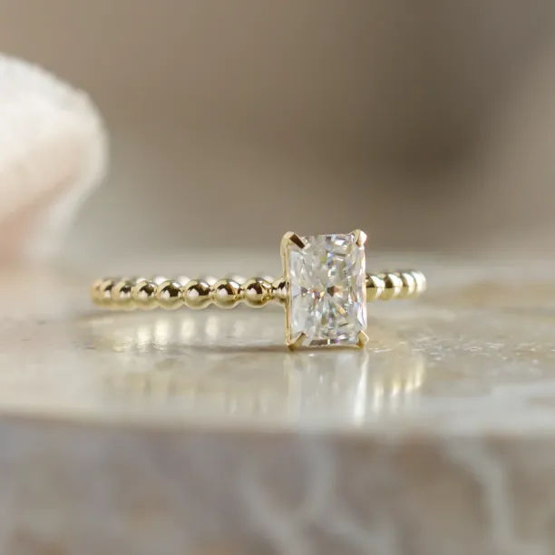 Close-up of CLEA beaded-ball engagement ring with radiant moissanite