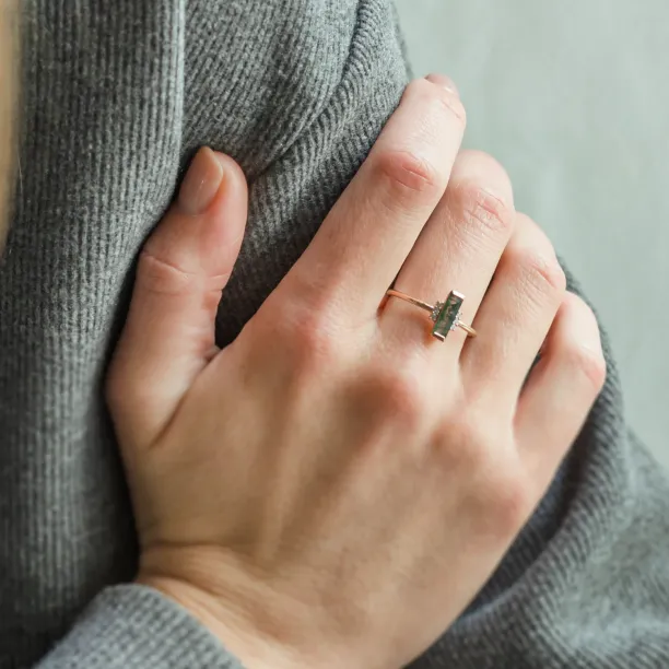 Close-up of the BRONTE engagement ring with baguette moss agate worn on the hand