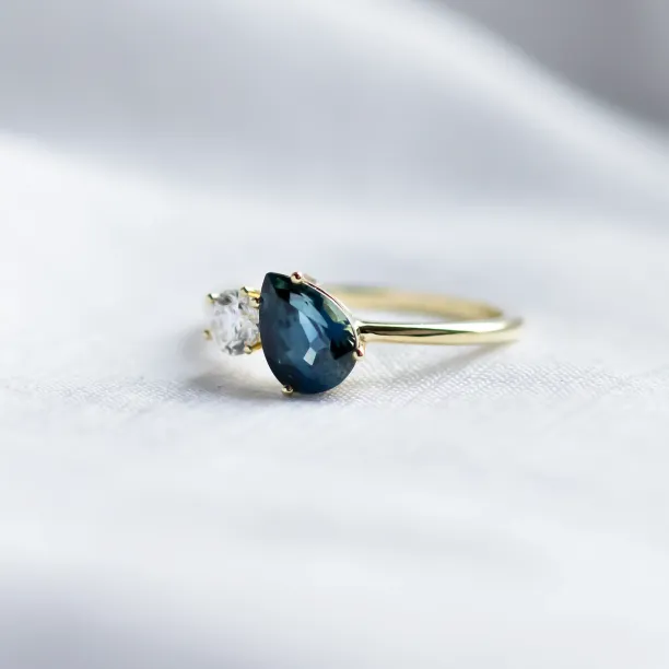 Angled view of the COUPLE Toi et Moi ring with blue pear sapphire and diamond